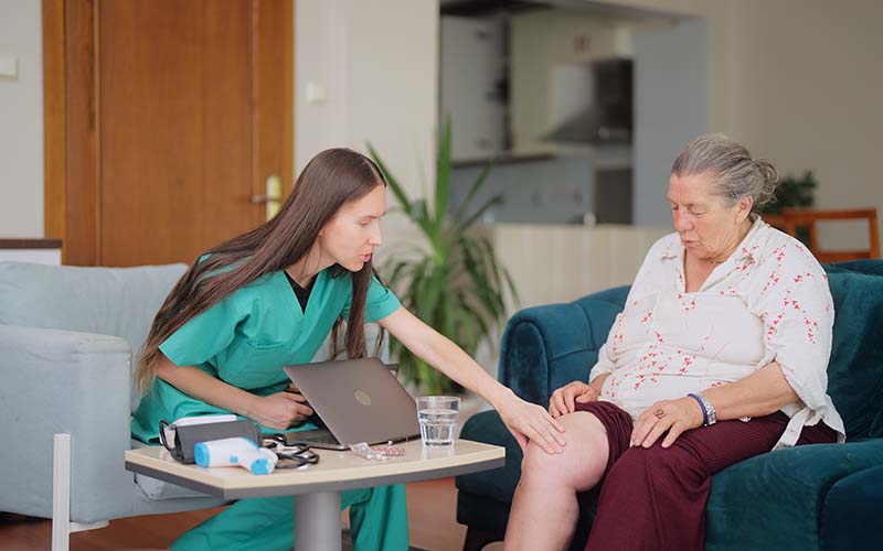 Female doctor visiting her elderly patient at her house for medical check